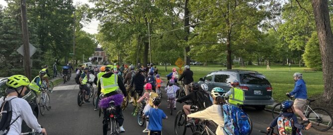 Children and adults walk, bike and roll across a marked crossing on their way to school, showing the sidewalks and street conditions along their route.