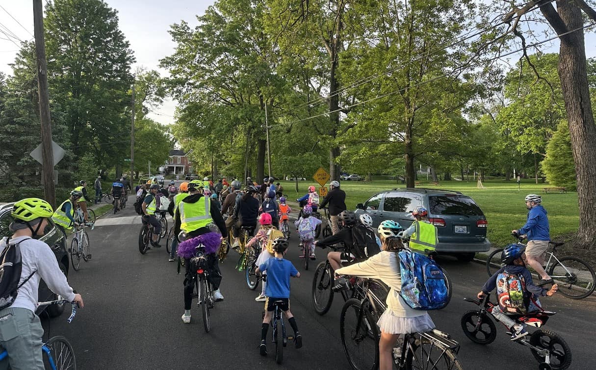 Children and adults walk, bike and roll across a marked crossing on their way to school, showing the sidewalks and street conditions along their route.